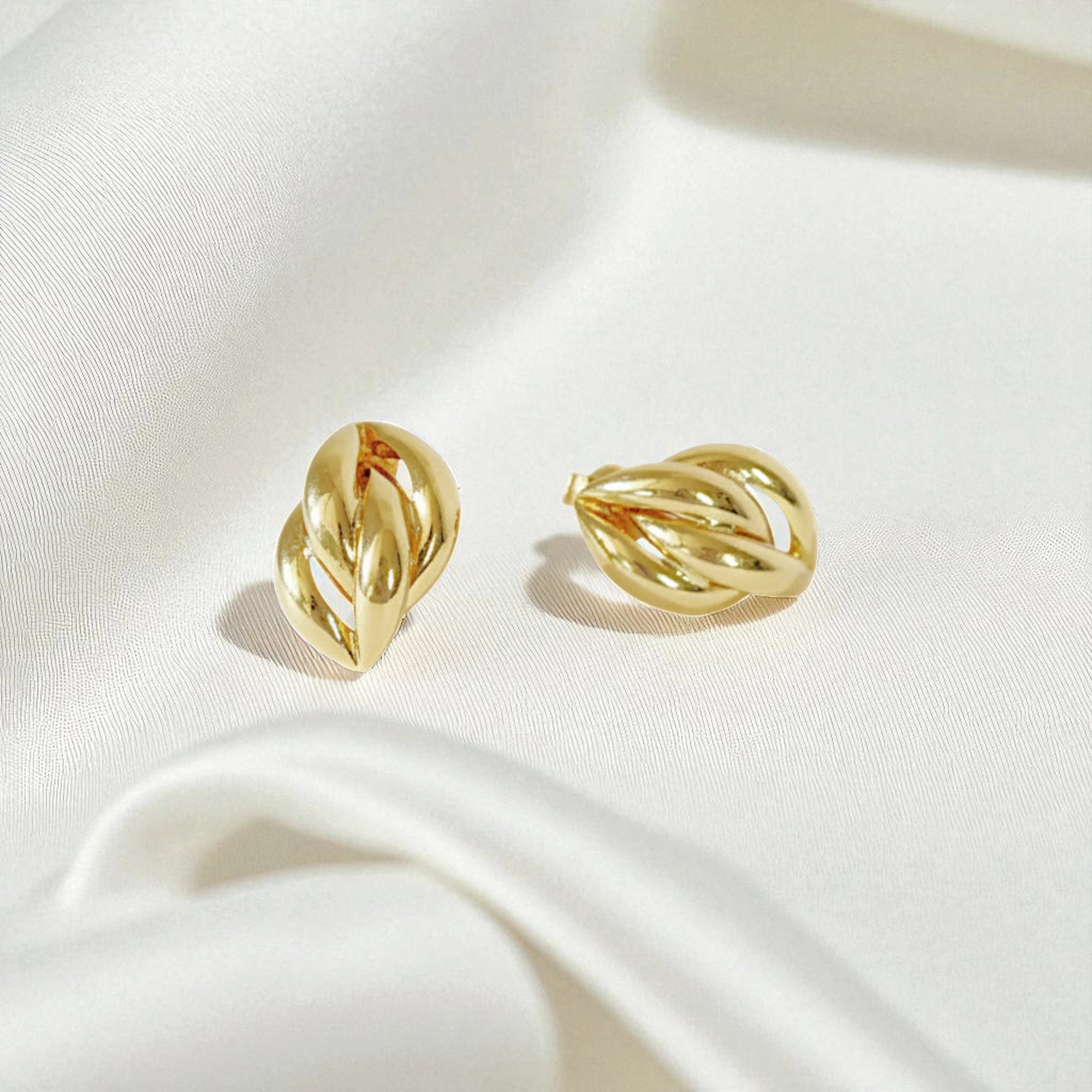 14 Karat Gold earrings on a white silk fabric background.