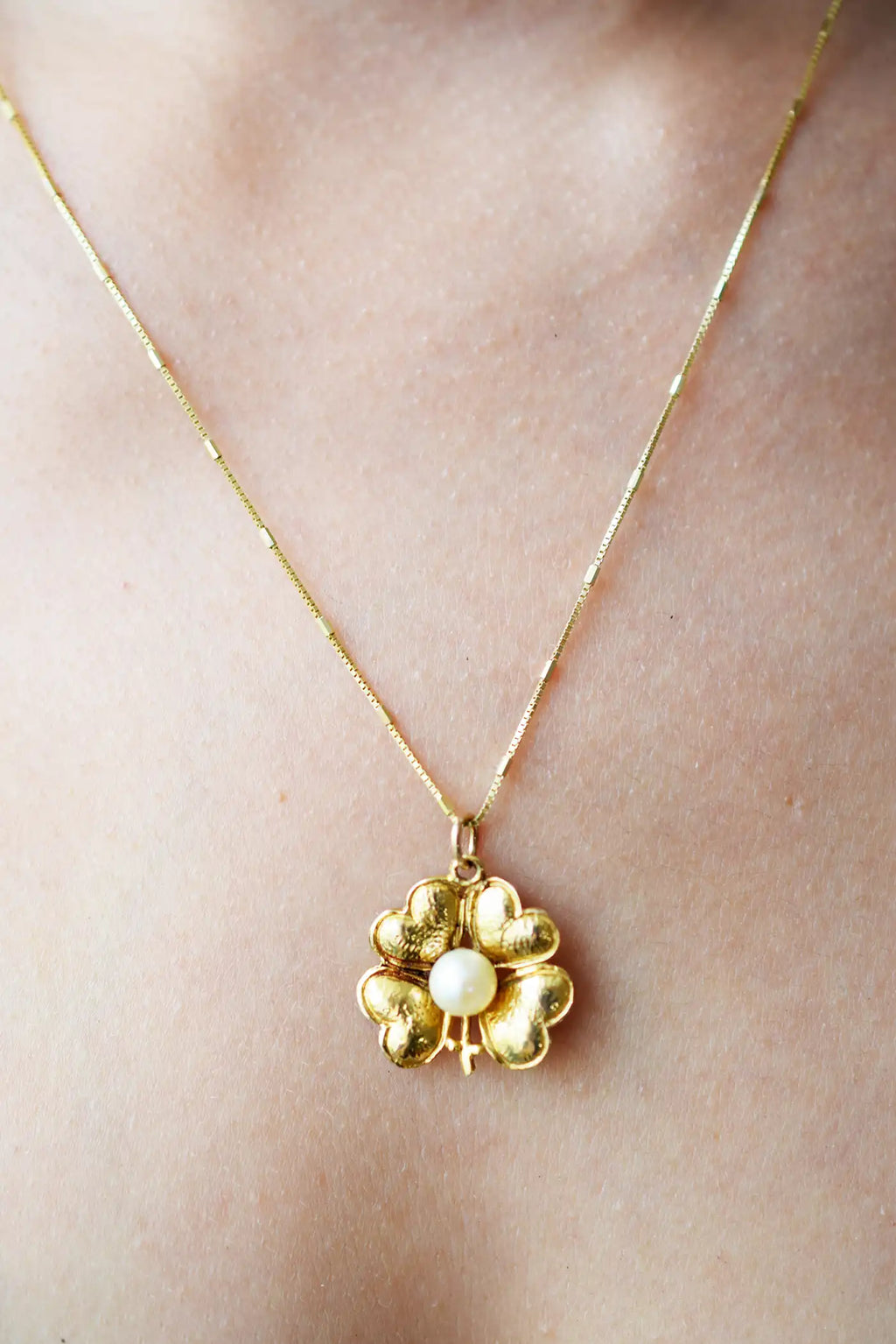 Antique 9 Karat Yellow Gold pendant featuring a central Freshwater Pearl, encircled by four heart-shaped leaves forming a vintage-style lucky clover, worn on a fine gold chain.