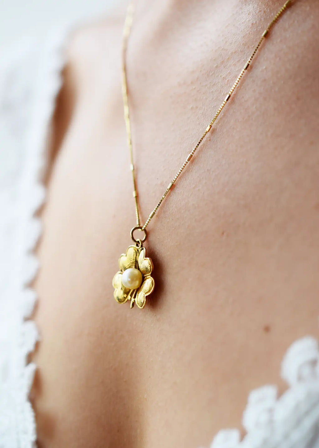 Antique 9 Karat Yellow Gold pendant featuring a central Freshwater Pearl, encircled by four heart-shaped leaves forming a vintage-style lucky clover, worn on a fine gold chain.