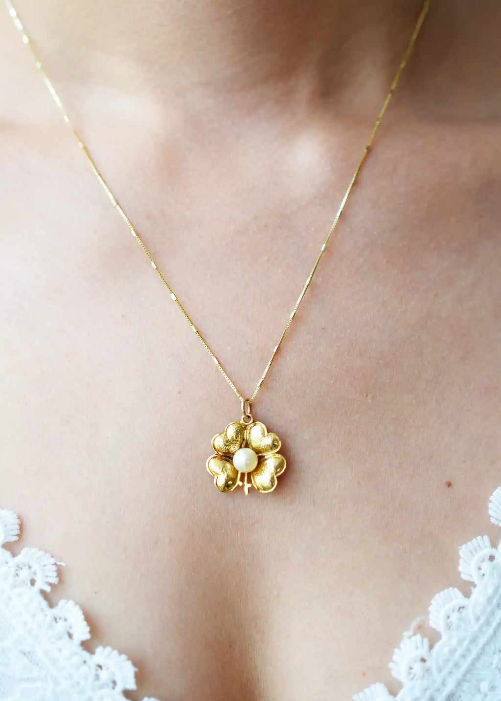 Antique 9 Karat Yellow Gold pendant featuring a central Freshwater Pearl, encircled by four heart-shaped leaves forming a vintage-style lucky clover, worn on a fine gold chain.