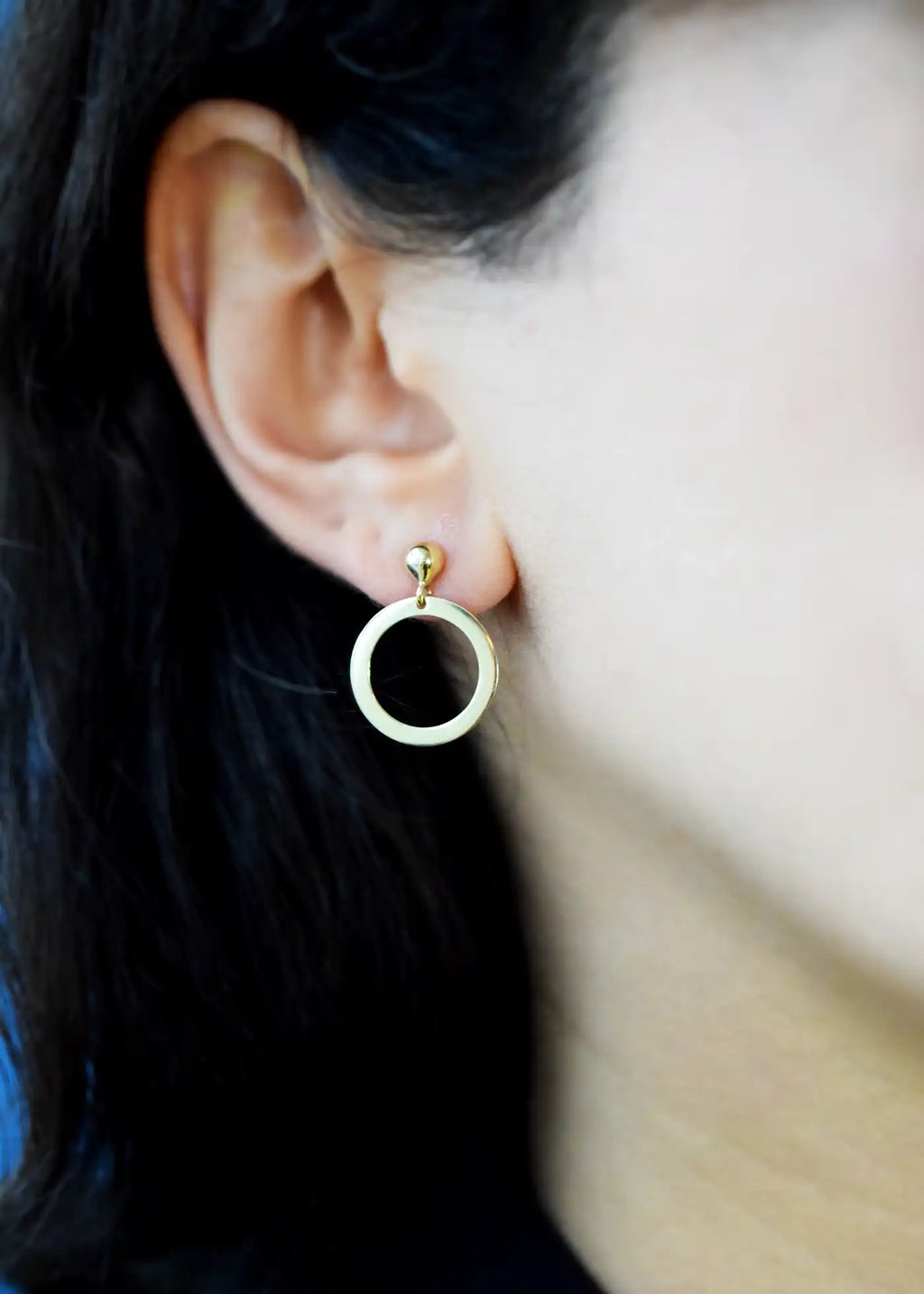 Elegant 14 Karat Yellow Gold delicate open circle drop earrings with a polished flat design, worn on a model's ear.