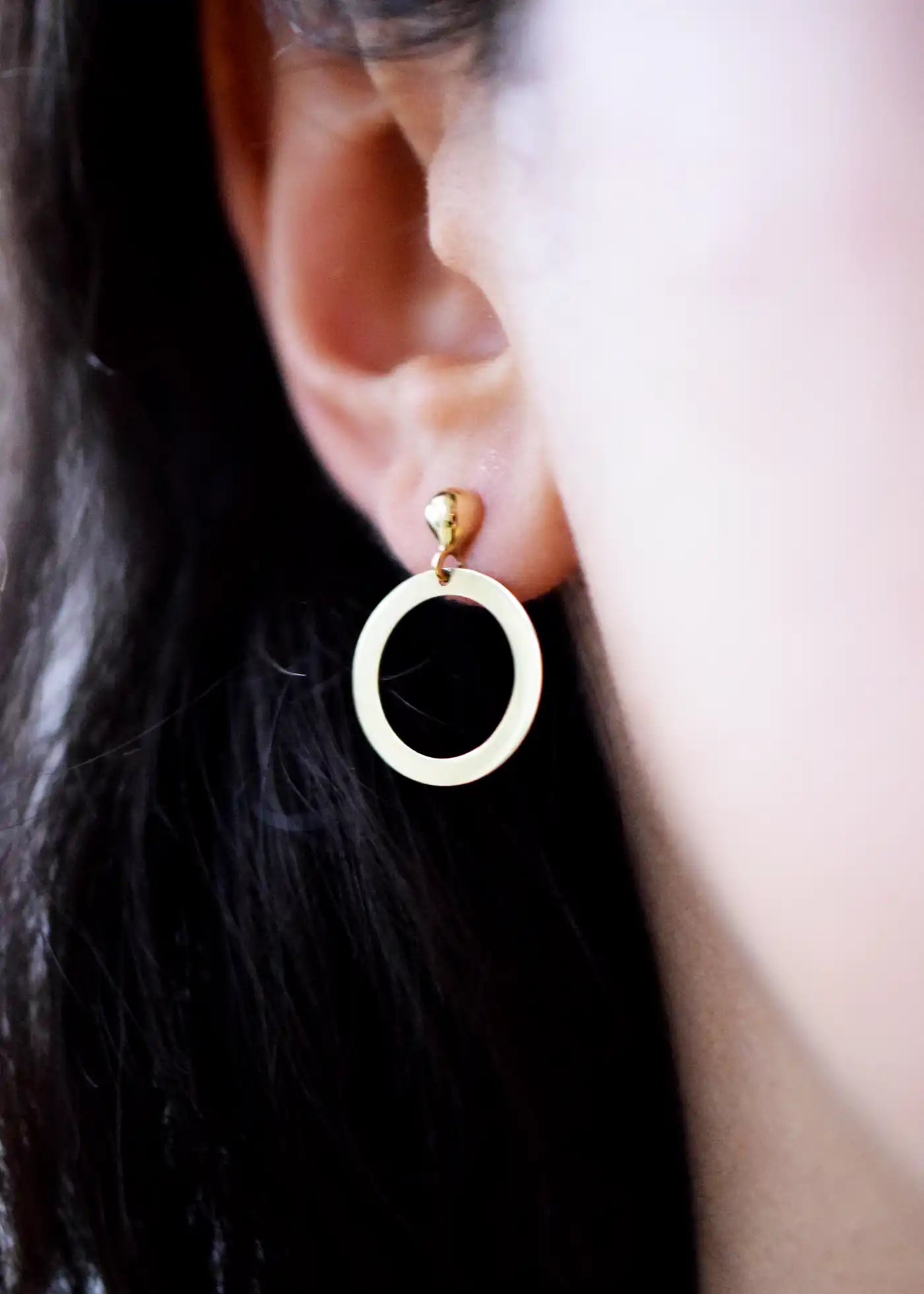 Elegant 14 Karat Yellow Gold delicate open circle drop earrings with a polished flat design, worn on a model's ear.