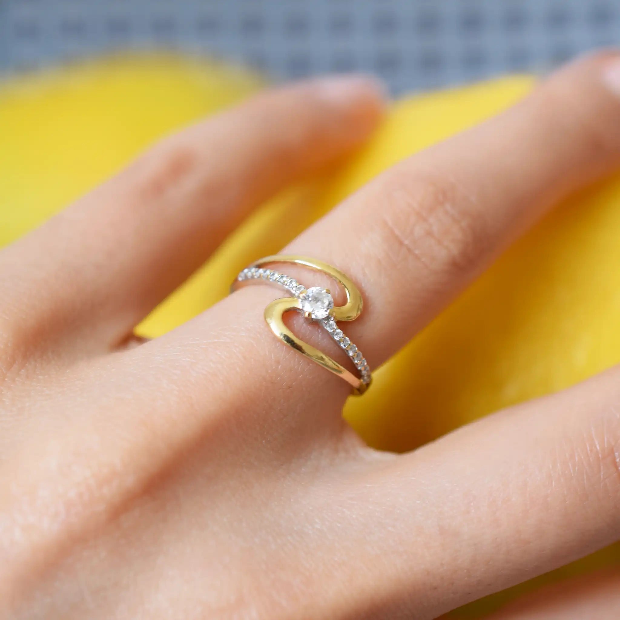 Elegant 18 Karat Yellow Gold Ring with a swirling design, featuring a Marquise Cubic Zirconia as the center stone and side accents of small zirconia stones.