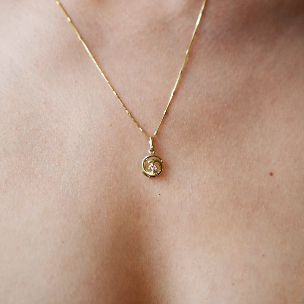 Elegant 8 Karat Yellow Gold pendant featuring a natural diamond nestled within a captivating spiral design, worn on a delicate gold chain.