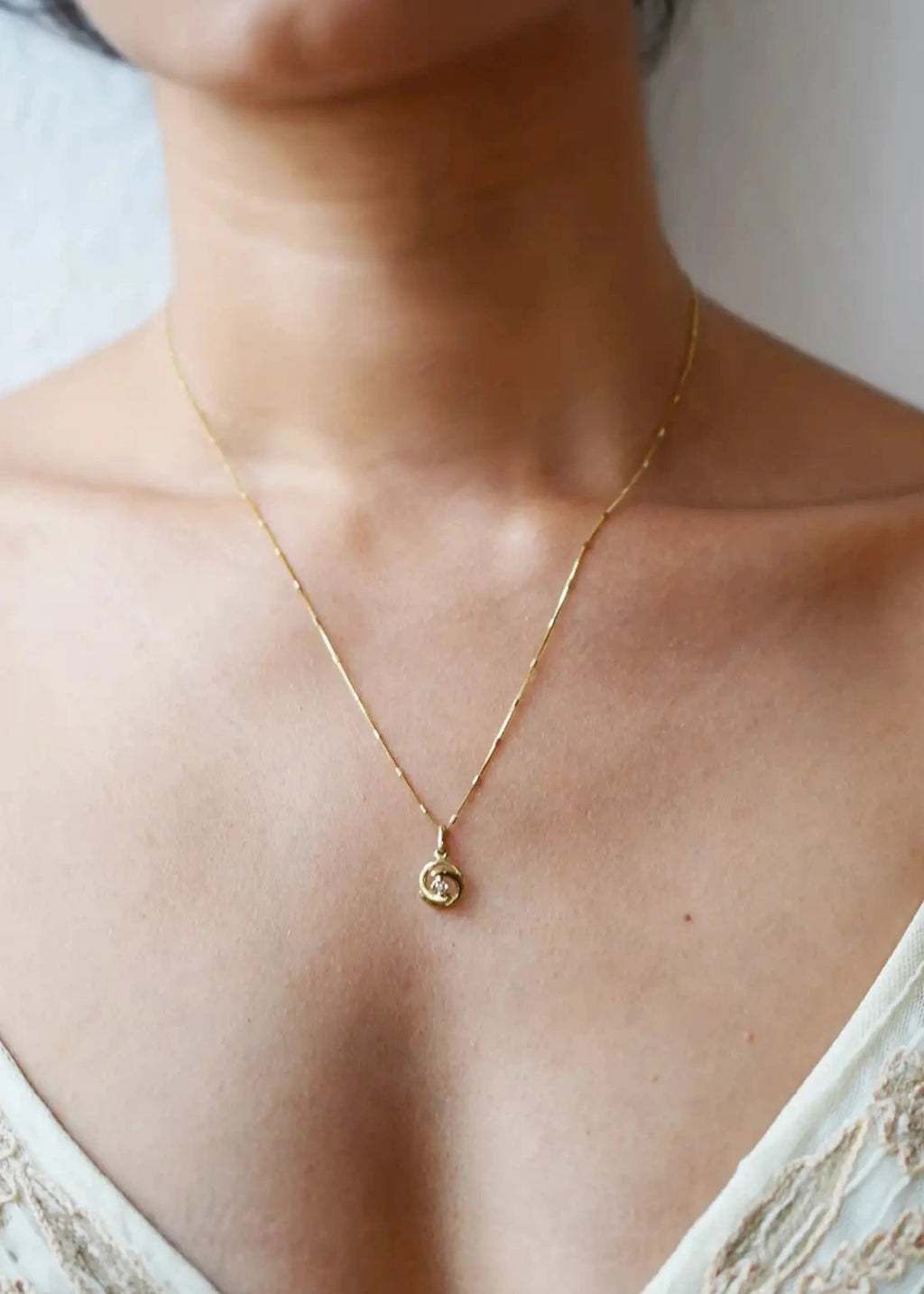 Elegant 8 Karat Yellow Gold pendant featuring a natural diamond nestled within a captivating spiral design, worn on a delicate gold chain.