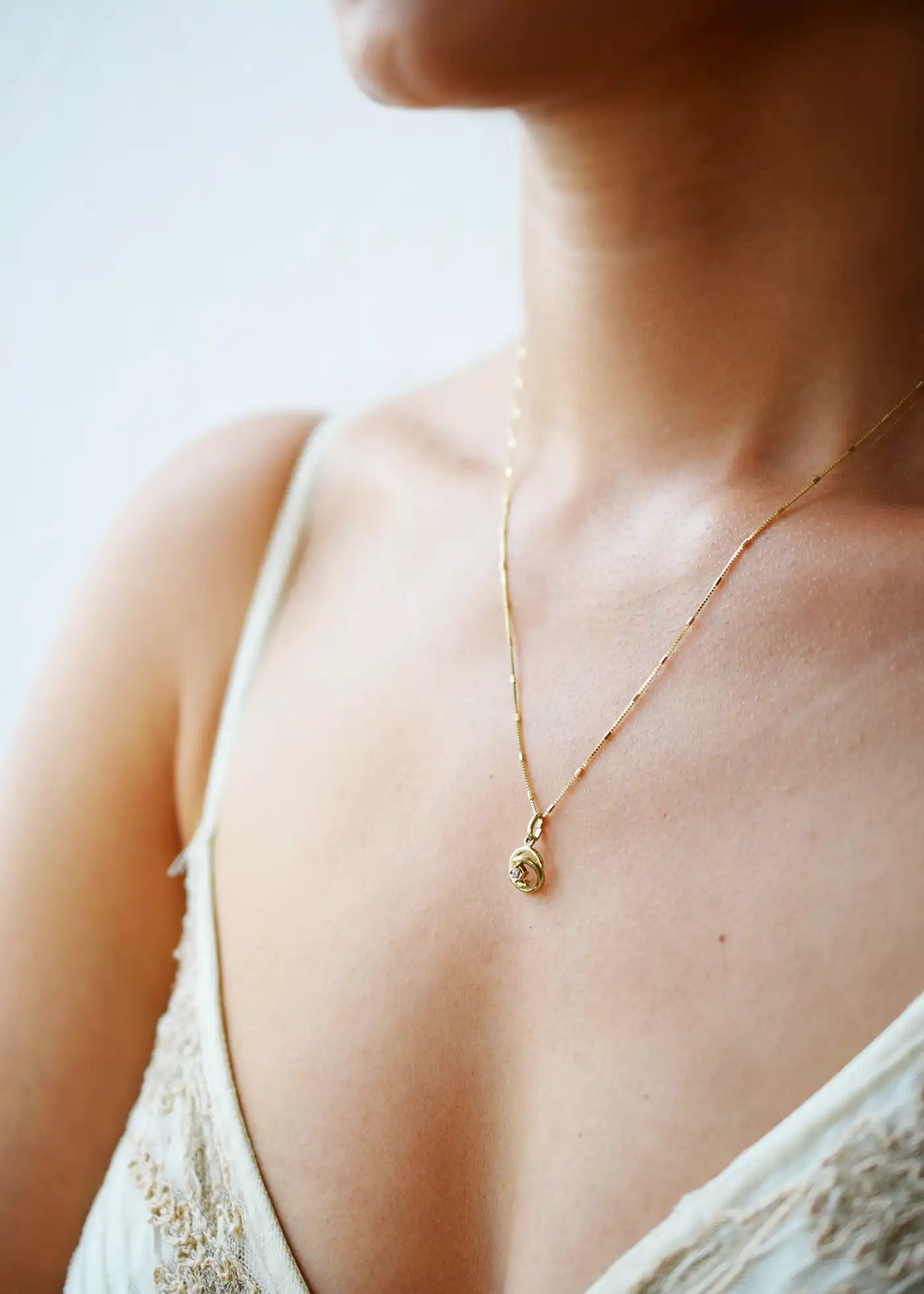 Elegant 8 Karat Yellow Gold pendant featuring a natural diamond nestled within a captivating spiral design, worn on a delicate gold chain.