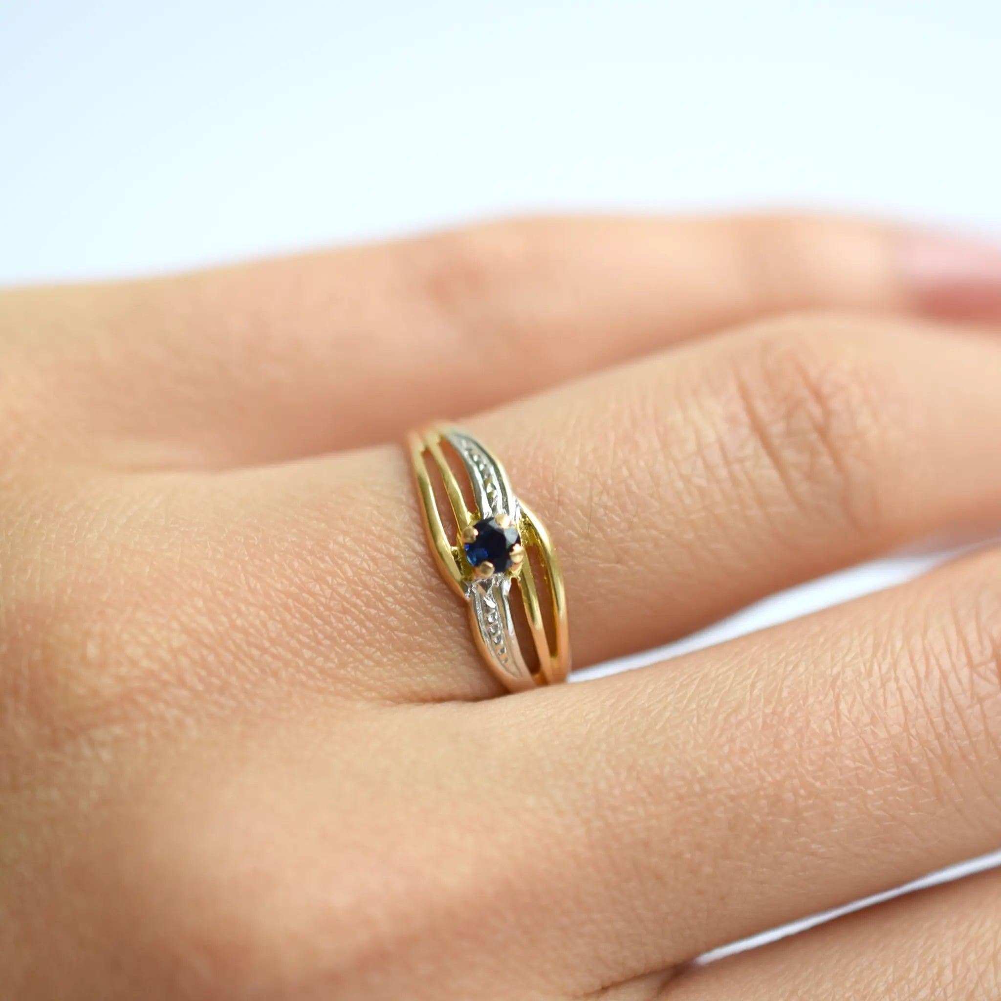 Elegant 18 Karat Yellow Gold ring featuring an oval blue sapphire, worn on a models hand.
