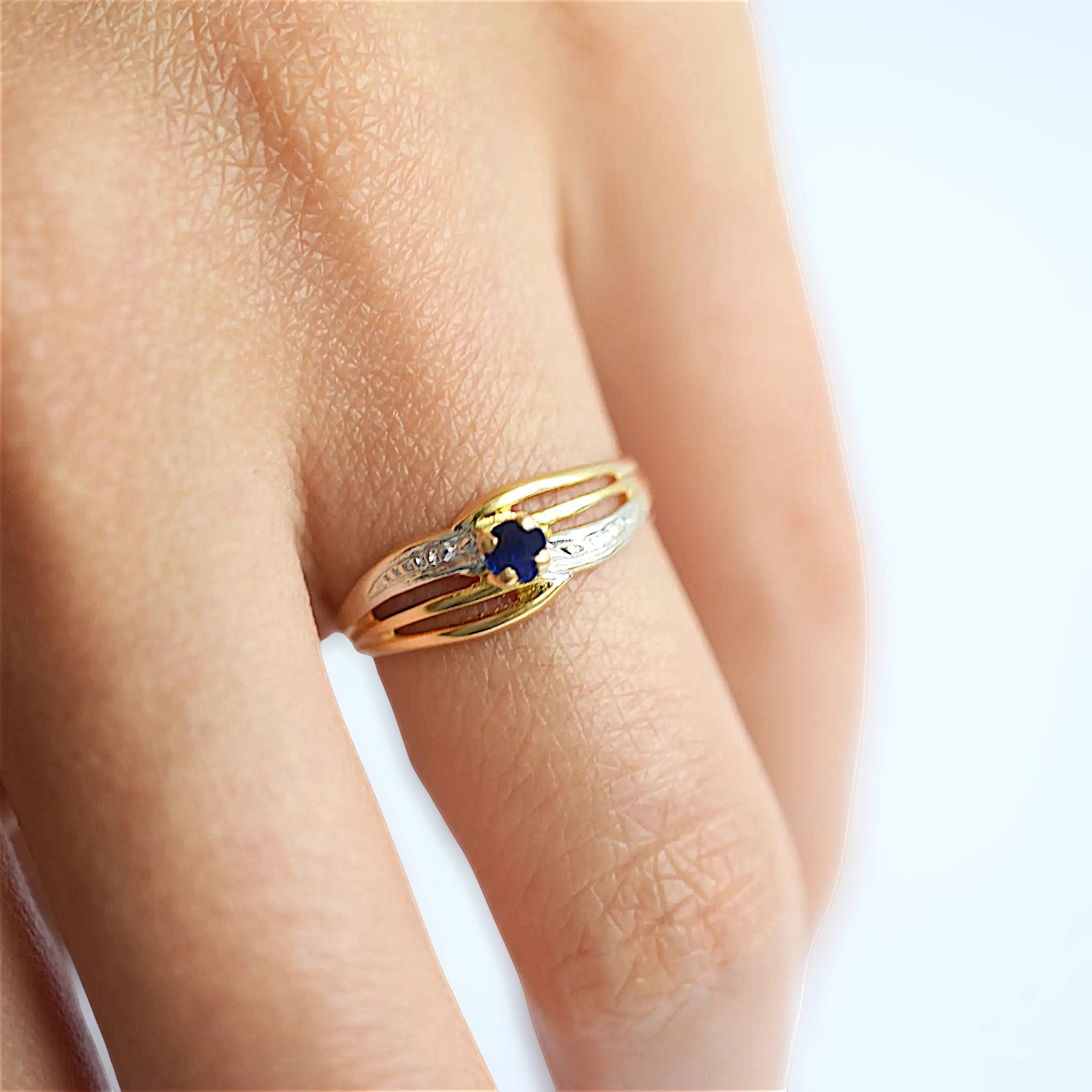 Elegant 18 Karat Yellow Gold ring featuring an oval blue sapphire, worn on a models hand.