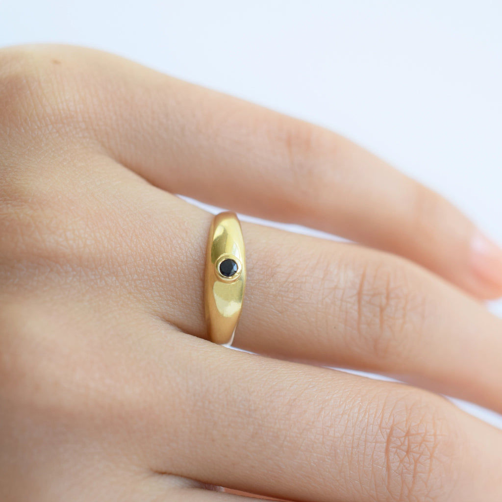 18 Karat Gold ring with a sapphire gemstone on a finger against a light background.