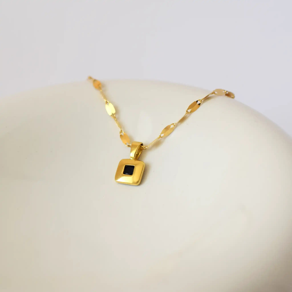 Elegant 18 Karat Yellow Gold vintage pendant featuring a polished, diamond-shaped design with a central bezel-set square sapphire.