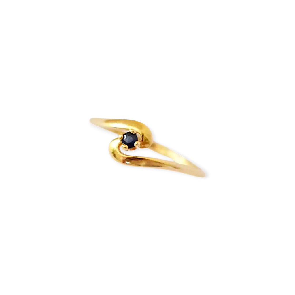 Elegant 18 Karat Yellow Gold vintage ring featuring a vibrant round blue sapphire set in a polished, curving bypass design.