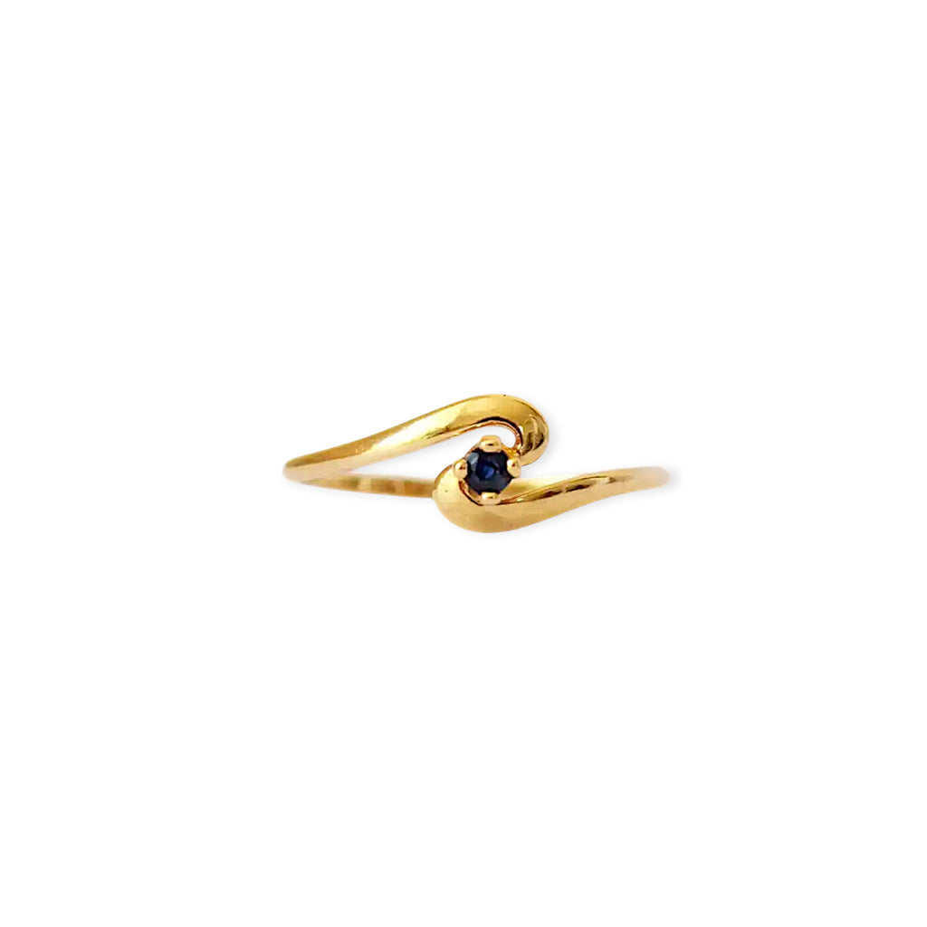 Elegant 18 Karat Yellow Gold vintage ring featuring a vibrant round blue sapphire set in a polished, curving bypass design.