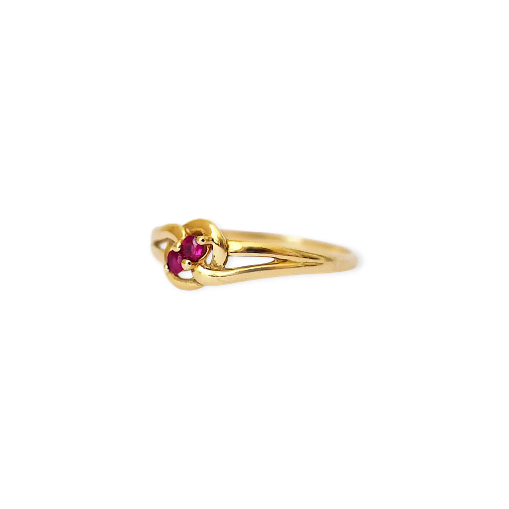 Elegant 18 Karat Yellow Gold vintage ring featuring two vibrant natural rubies nestled in a polished, swirling bypass setting.