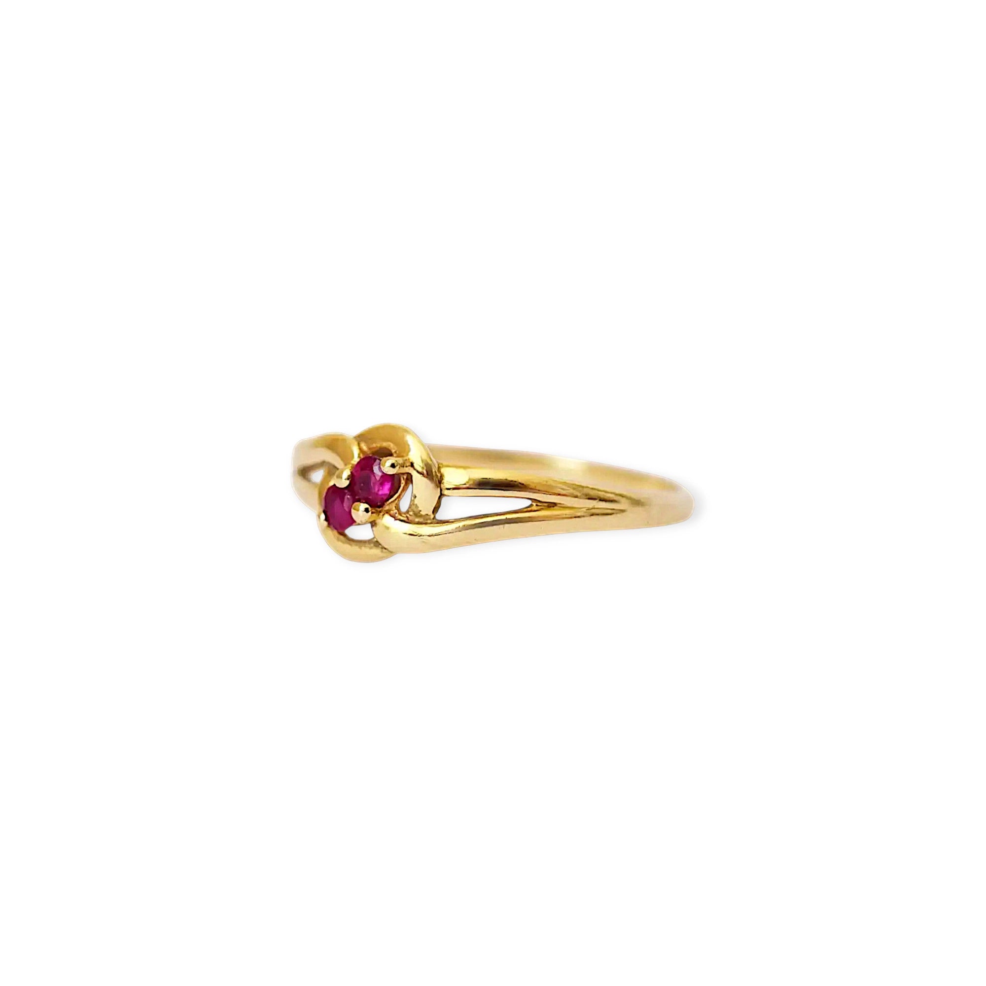 Elegant 18 Karat Yellow Gold vintage ring featuring two vibrant natural rubies nestled in a polished, swirling bypass setting.