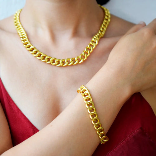 Luxurious 21 Karat Yellow Gold bold flat curb chain bracelet, featuring an ornate clasp with black-enameled ornamental elements in a classic Greek key pattern.