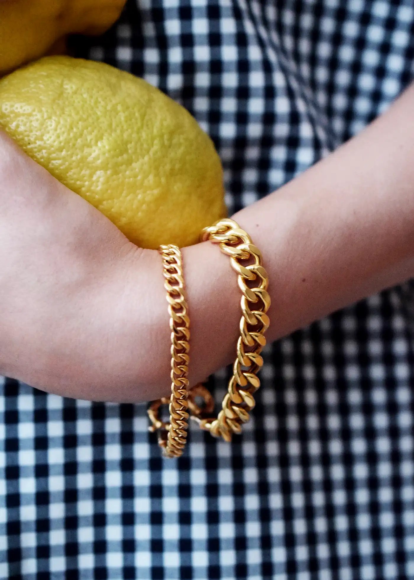 Luxurious 21 Karat Yellow Gold bold flat curb chain bracelet, featuring an ornate clasp with black-enameled ornamental elements in a classic Greek key pattern.