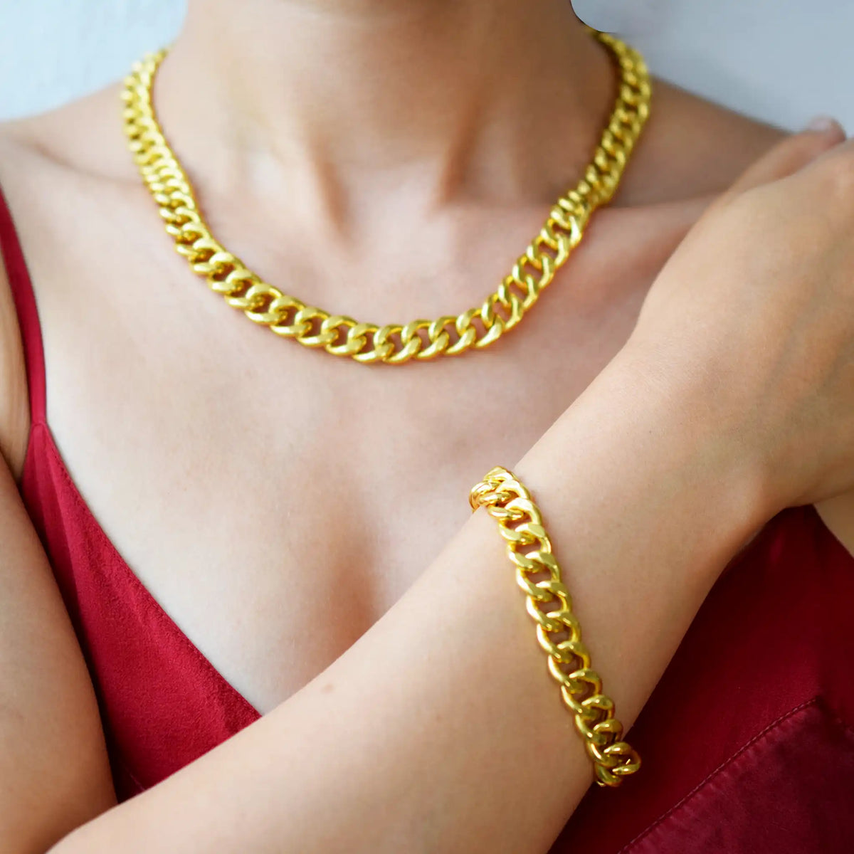 Luxurious 21 Karat Yellow Gold bold flat curb chain necklace, featuring an ornate clasp with black-enameled ornamental elements in a classic Greek key pattern, worn on a model's neck