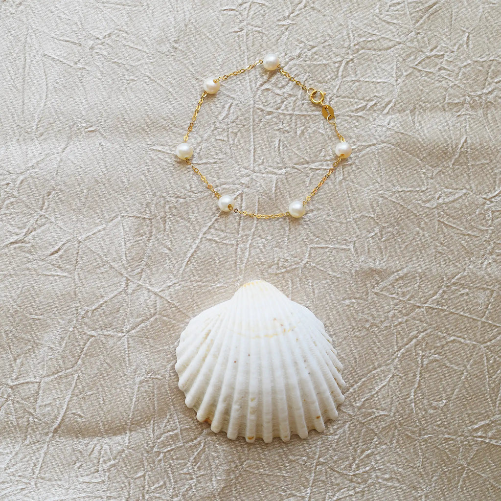 Romantic 18 Karat Yellow Gold bracelet showcasing glowing freshwater pearls along a delicate link chain.