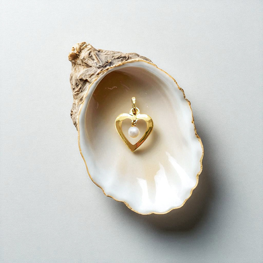 Romantic 18 Karat Yellow Gold heart pendant featuring a suspended freshwater pearl inside an open shell on a light gray background.