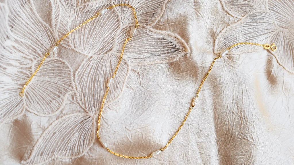 Romantic 18 Karat Yellow Gold necklace featuring irregularly shaped freshwater pearls stationed along a delicate link chain.