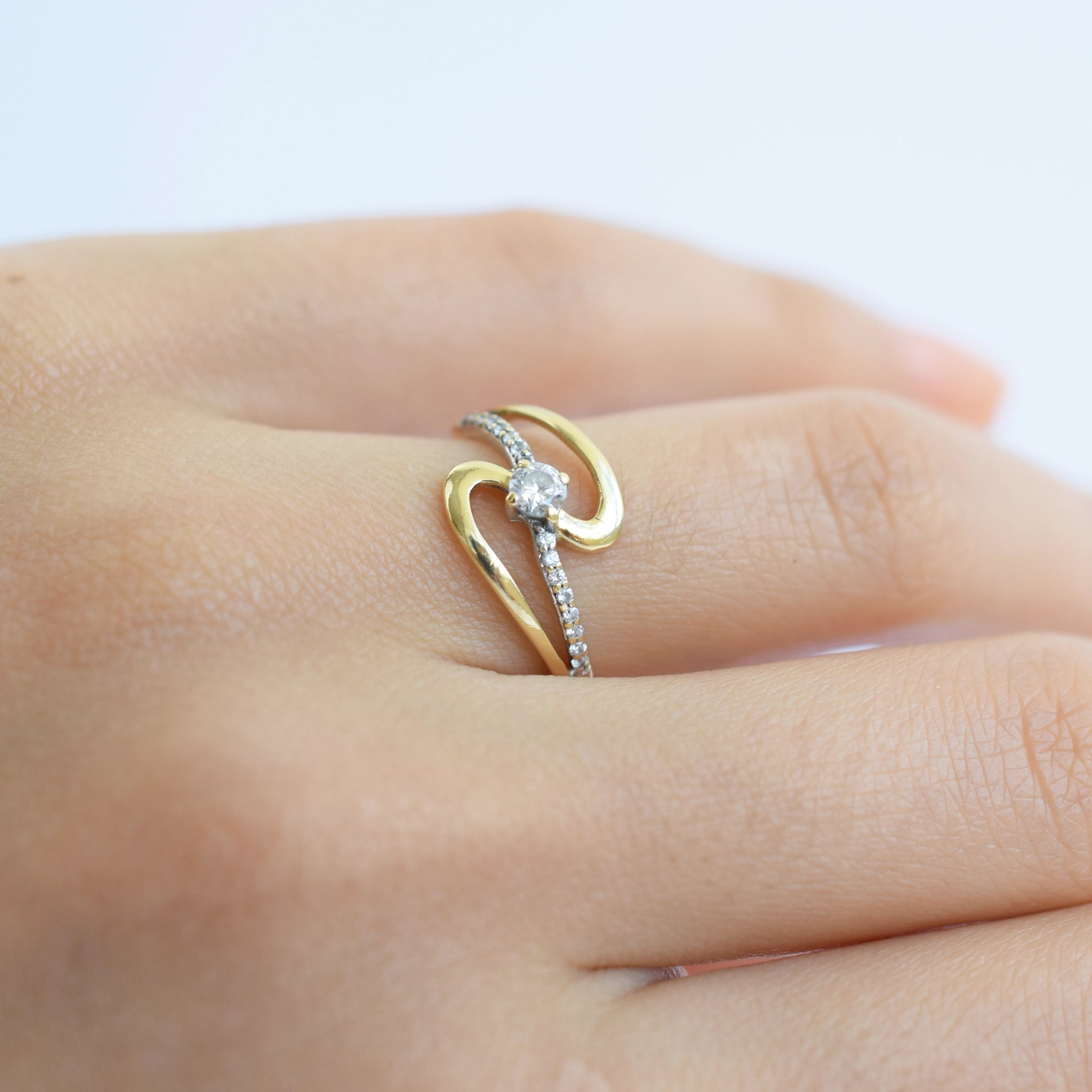 18 Karat Gold Ring with Zirconia stones on a finger against a light background.